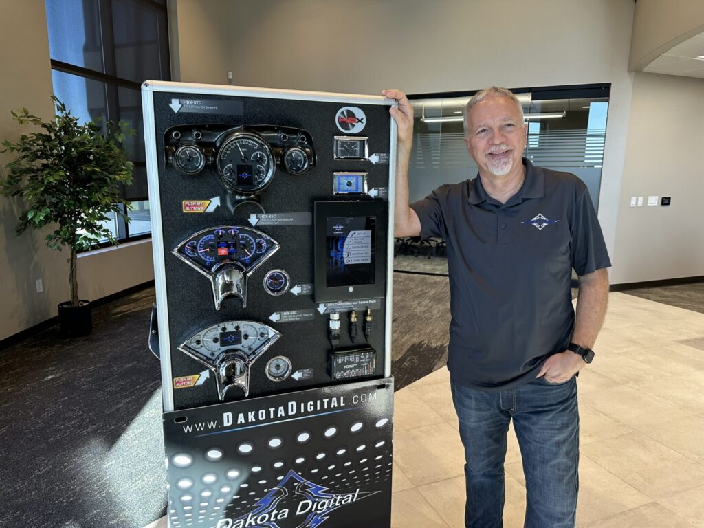 Dakota Digital Owner Ross Ortman stands with display of gauges