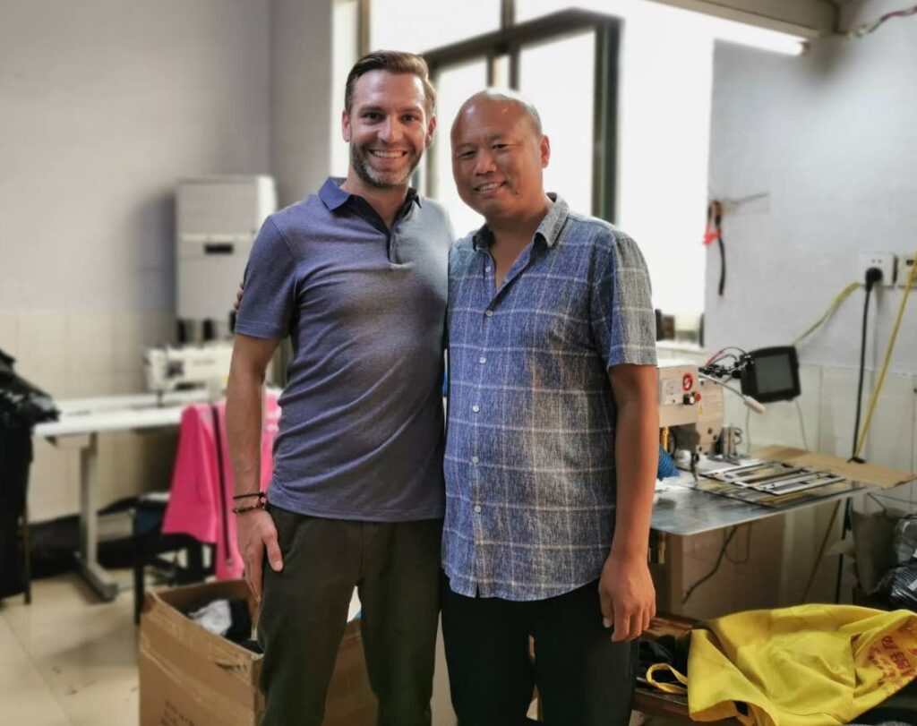 Two men smiling for a photo in a sewing room