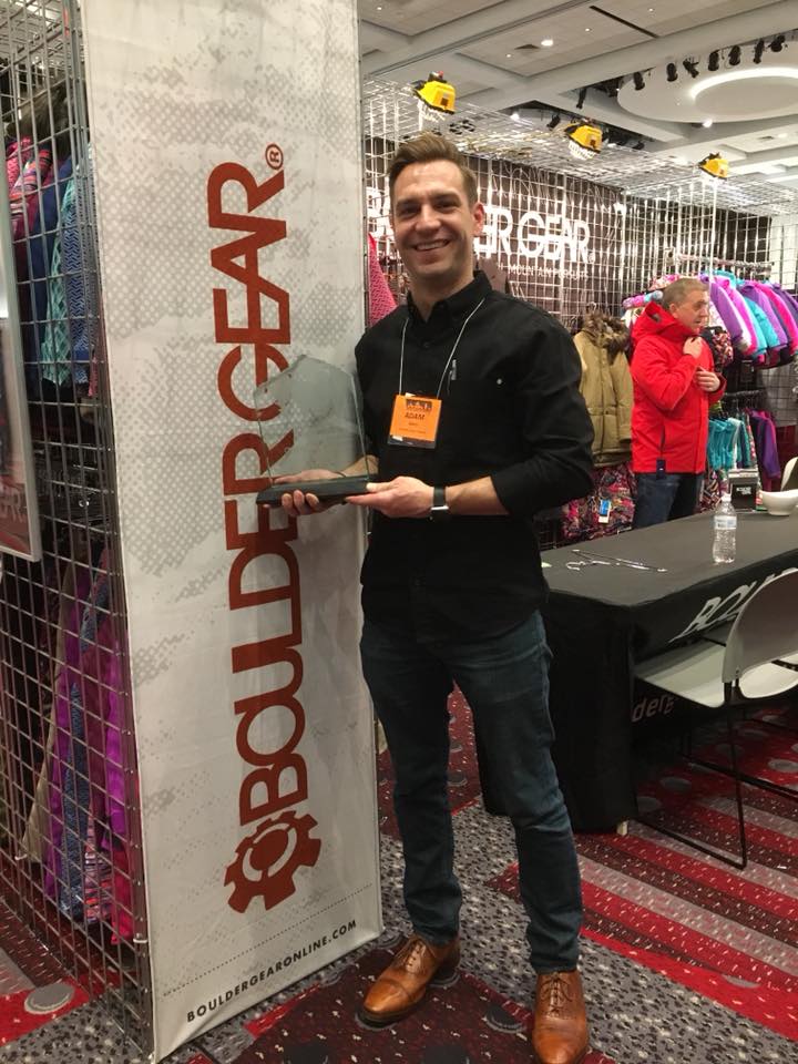 Adam Garry with award plaque next to Boulder Gear banner