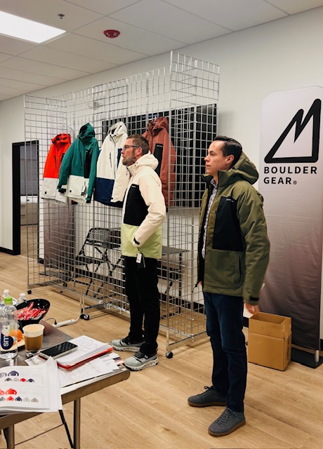 Two men wearing coats in front of a Boulder Gear display.